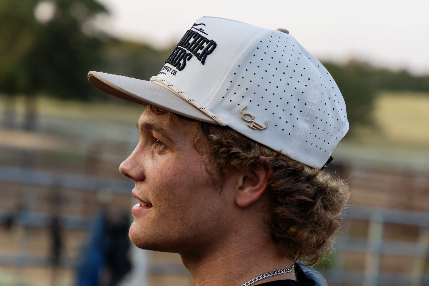 Man wearing a beige cap with Cowpuncher Thread Co. branding, outdoors