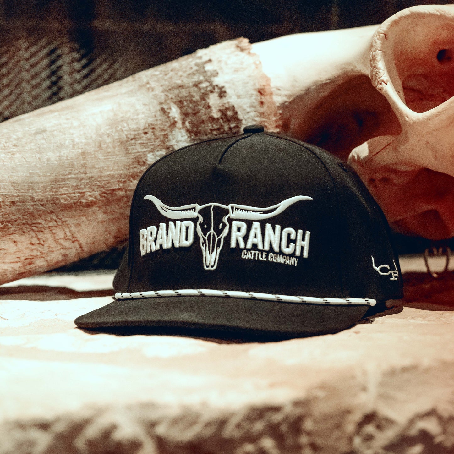 Black snapback cap, with the text Brand Ranch, in white embroidery.
