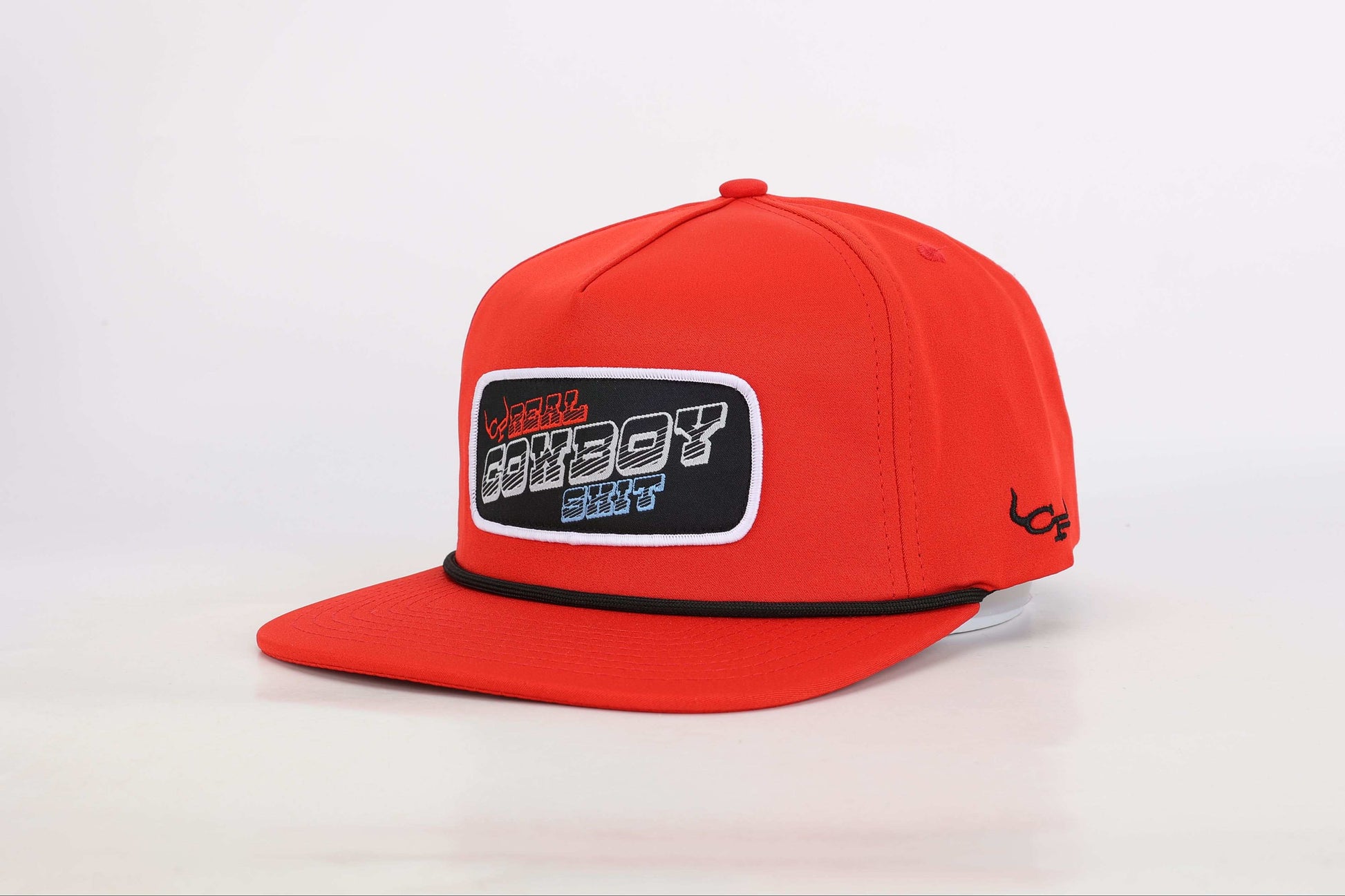 Red snapback cap with a woven patch that reads 'Real Cowboy Shit'. Angled View