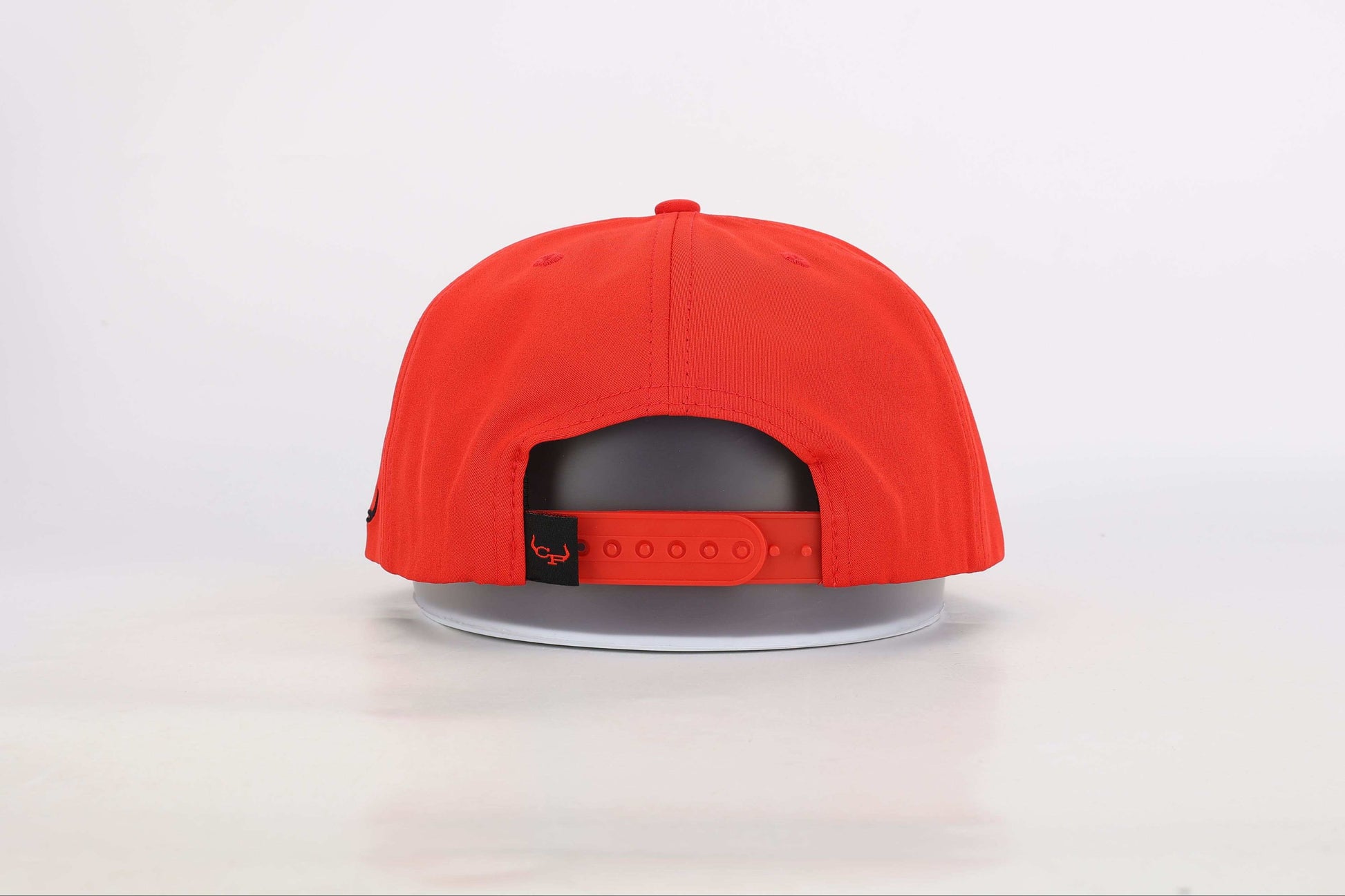 Red snapback cap with a woven patch that reads 'Real Cowboy Shit'. Back View