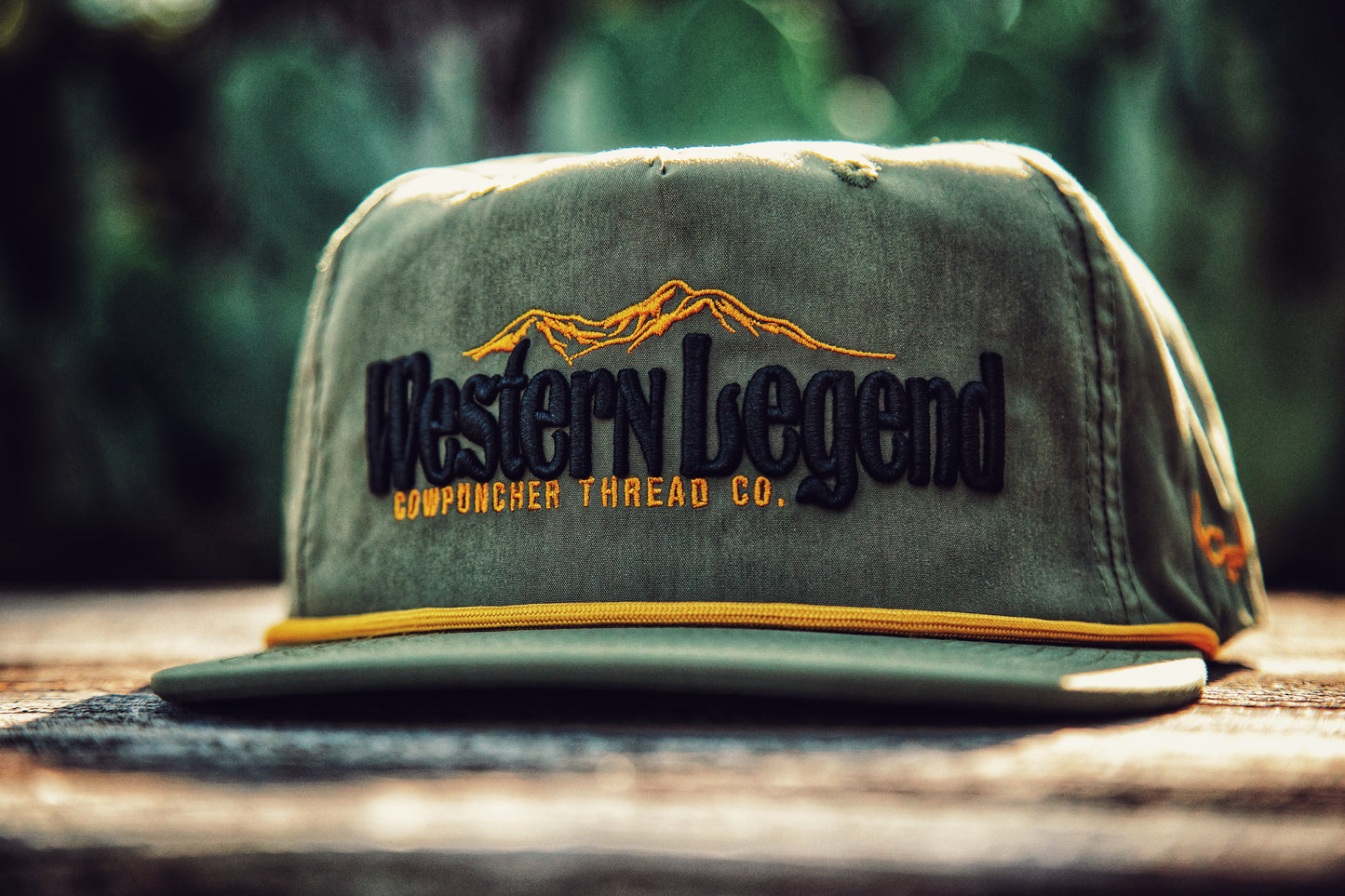 Green cap with 'Western Legend' embroidery on a surface with a cactus  background