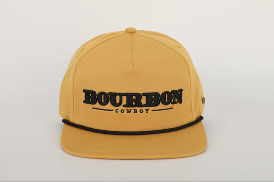 A mustard yellow snapback hat with 'BOURBON COWBOY' embroidered on the front. Front View