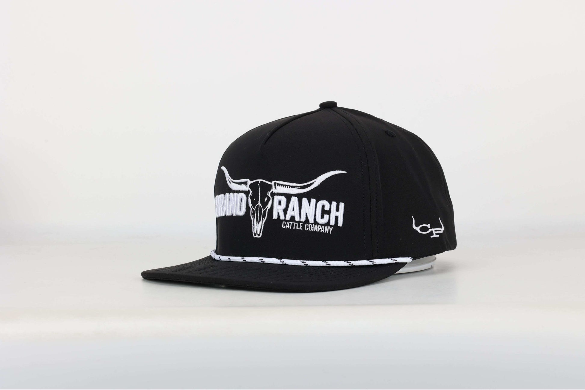 Black cap with a embroidered logo of a longhorn with texts that says 'BRAND RANCH' in white bold 3d embroidery. Angled View