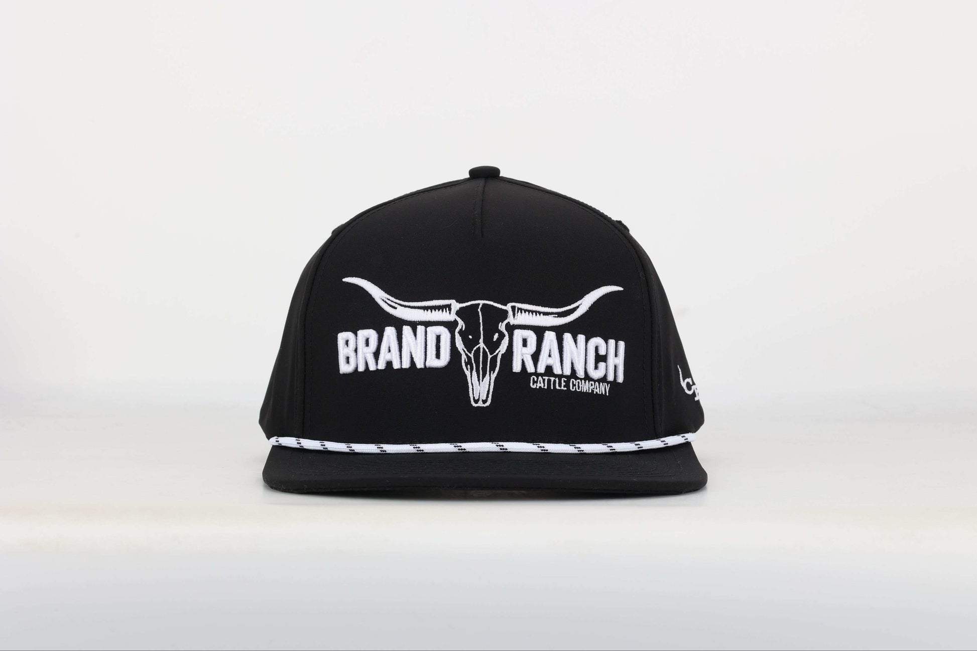 Black cap with a embroidered logo of a longhorn with texts that says 'BRAND RANCH' in white bold 3d embroidery. Front View
