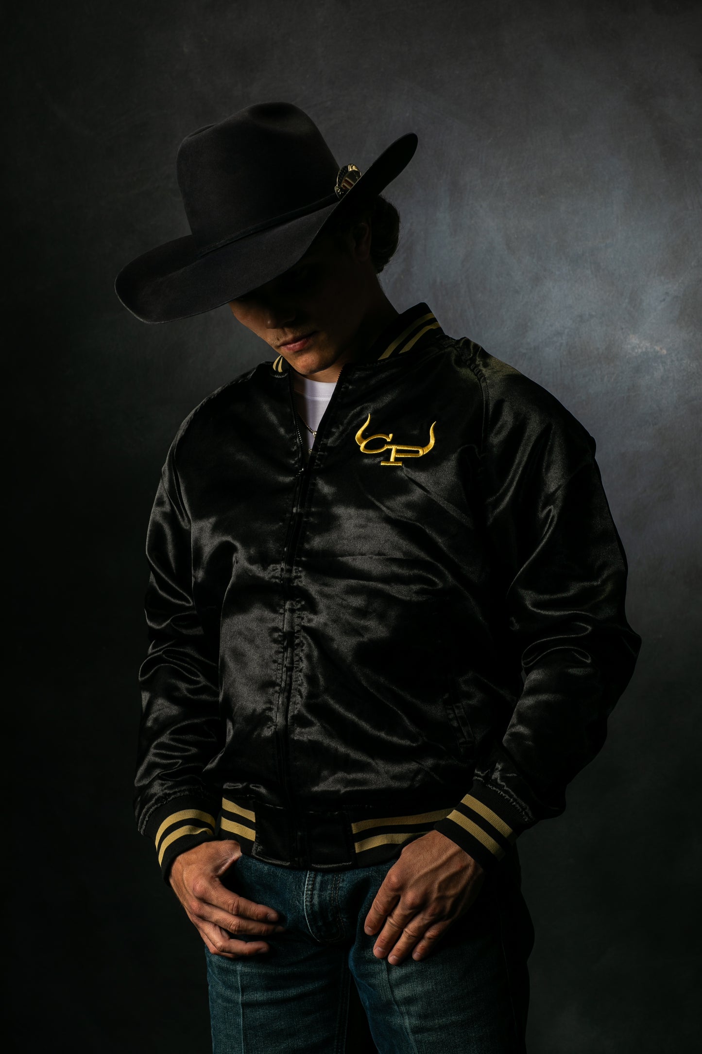 Gavan Hauck wearing a black satin rodeo bomber jacket, with gold CP Brand with horns.